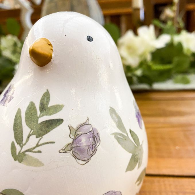 Decorative ceramic bird with floral designs on a wooden surface. Painted Floral Porcelain Bird available at Quilted Cabin Home Decor.