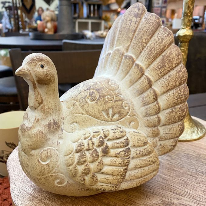 Decorative resin turkey figure on a wooden surface with a blurred indoor background. Weathered Resin Turkey available at Quilted Cabin Home Decor.