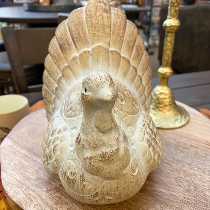Decorative stone turkey figurine on a wooden surface with a blurred background. Weathered Resin Turkey available at Quilted Cabin Home Decor.
