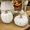 Two white marbled pumpkins on a wooden surface with a blurred indoor background. White Carved Pumpkins - Two Styles available at Quilted Cabin Home Decor.