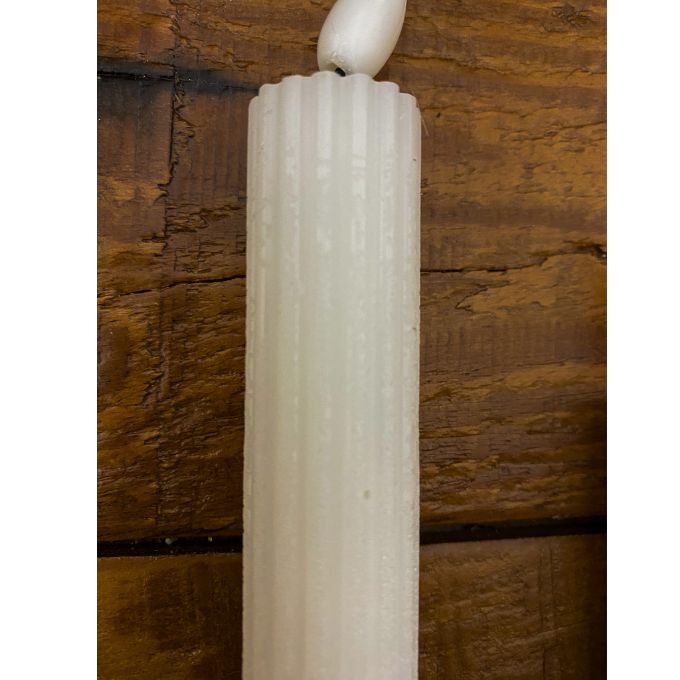 Textured white candle against a wooden background. White Ridged LED Timer Taper Candles - Two Sizes available at Quilted Cabin Home Decor.