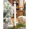 Tall white candle in a wooden holder on a table with a Christmas tree and decorative items in the background. White Ridged LED Timer Taper Candles - Two Sizes available at Quilted Cabin Home Decor.