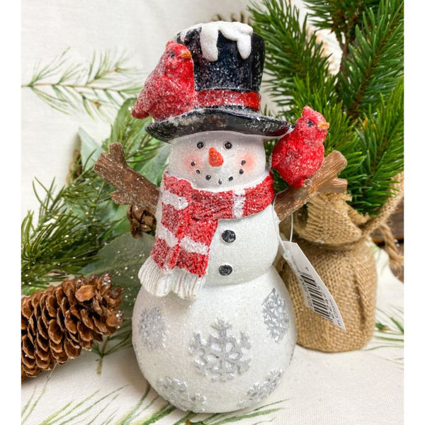 A resin snowman with a black top hat and red scarf is a figurine for your holiday decor. It has red cardinals on its hat and arm. Available at Quilted Cabin Home Decor.