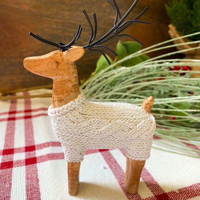 A Small Sweater Deer Figurine. The deer is wearing a cozy white cable knit sweater. Available at Quilted Cabin Home Deco