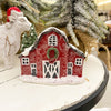 Decorative red barn figurine with snow on a white surface, Christmas tree in the background. Snowy Red Barn Figurine available at Quilted Cabin Home Decor.