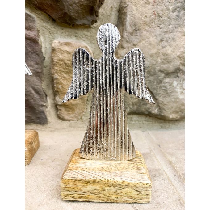 Metal angel sculpture on a wooden base against a stone wall background. Midnight Shimmer Angels - Two Sizes available at Quilted Cabin Home Decor.