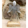 Metal angel sculpture on a wooden base against a stone wall background. Midnight Shimmer Angels - Two Sizes available at Quilted Cabin Home Decor.