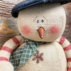 A burlap snowman with long limbs with red candy cane style stripes. It has a tall black hat and  a a green fabric scary. It is available at Quilted Cabin Home Decor.