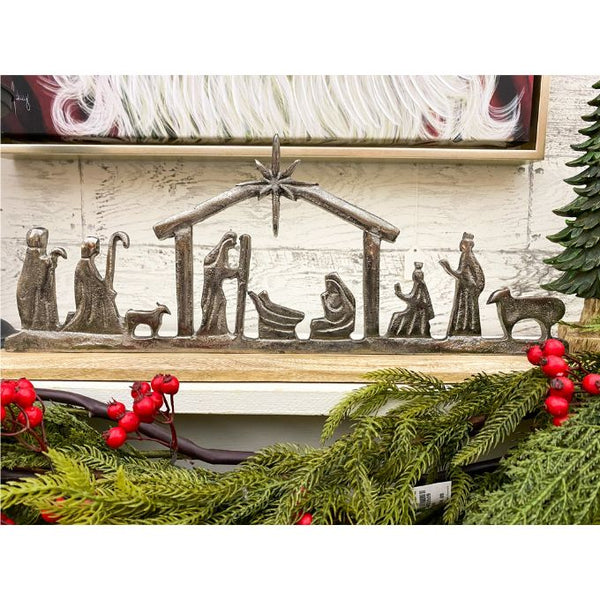 Decorative nativity scene with greenery and red berries on a white wall. Nativity Silhouette available at Quilted Cabin Home Decor.