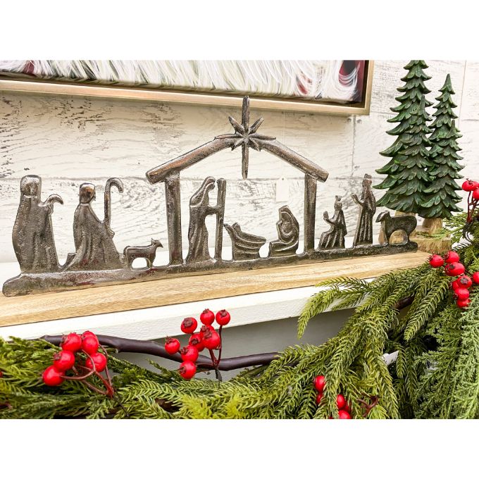 Decorative nativity scene on a mantel with greenery and red berries. Nativity Silhouette available at Quilted Cabin Home Decor.