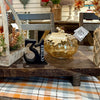 A decorative amber glass pumpkin with a leaf topper and a hanging 'Blessed' tag, displayed on a wooden table alongside a black number 3 and an October date marker in a rustic home decor setting. Available at Quilted Cabin in Airdrie