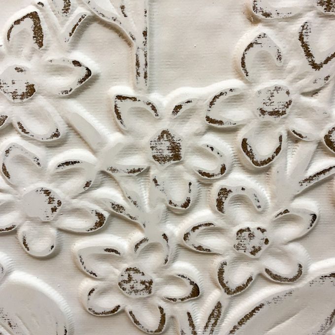 Close-up of floral embossed pattern on a textured surface. Embossed Whitewashed Flower Frame available at Quilted Cabin Home Decor.
