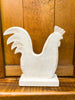 White wooden rooster figurine on a wooden surface with a wooden panel background. Whitewashed Wooden Hen on Stand available at Quilted Cabin  Home Decor. 