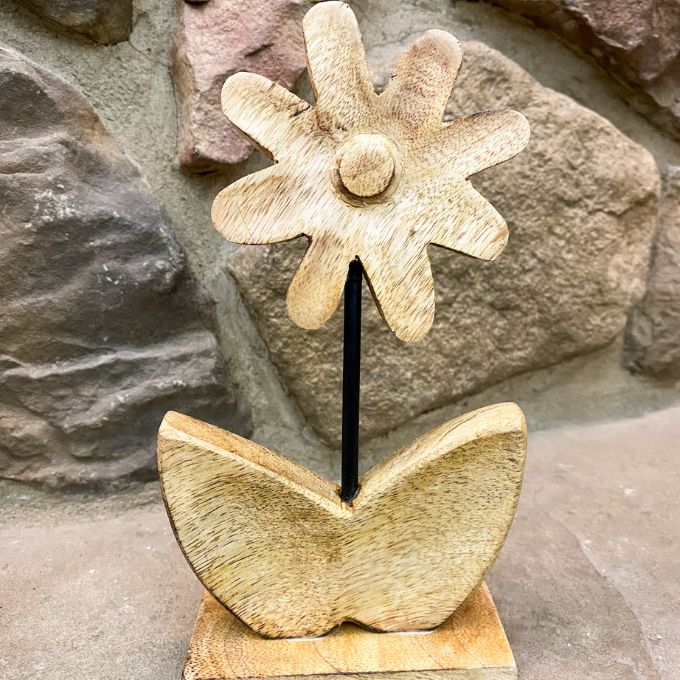 Decorative wooden flower sculpture against a stone wall. Wooden Daisies on Stand - Set of Two available at Quilted Cabin Home Decor.