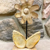 Decorative wooden flower sculpture against a stone wall background. Wooden Daisies on Stand - Set of Two available at Quilted Cabin Home Decor.