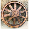 Decorative wooden wheel with a rustic finish against a stone wall. Wooden Wagon Wheels - Two Sizes available at Quilted Cabin  Home Decor.