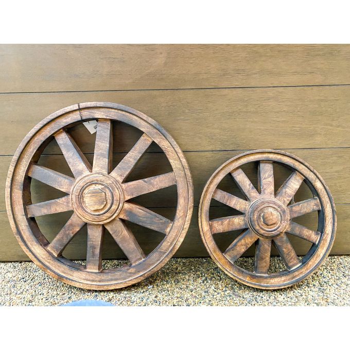 Two rustic wooden wheels against a wooden background. Wooden Wagon Wheels - Two Sizes available at Quilted Cabin  Home Decor.
