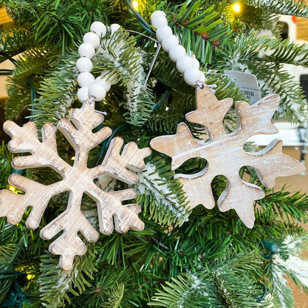 White distressed wooden snowflake ornaments in two different styles on white beaded hangers available at Quilted Cabin Home Decor.