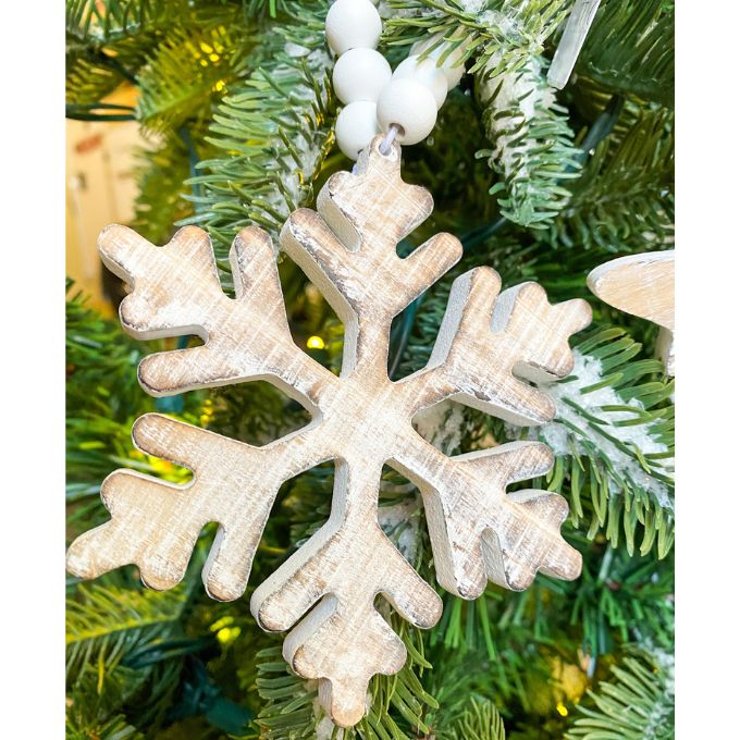 White distressed wooden snowflake ornaments in two different styles on white beaded hangers available at Quilted Cabin Home Decor.