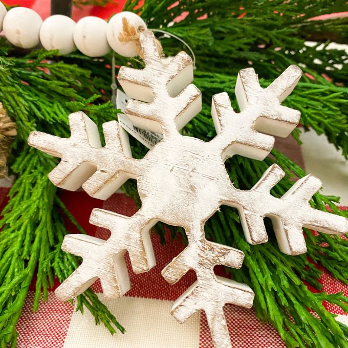 Distressed White Snowflake Hanger with Beaded Tassel is shown with a garland as part of a table display. Available at Quilted Cabin Home Decor.