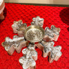 Decorative metal candle holder with snowflake designs on a red textured surface. Vintage Snowflake Tea Light Holder available at Quilted Cabin Home Decor.
