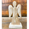 Wooden angel figurine on a wooden base with a rustic wooden background. Distressed White Wooden Angel available at Quilted Cabin Home Decor.