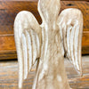 Wooden angel figurine with detailed wings on a wooden surface. Distressed White Wooden Angel available at Quilted Cabin Home Decor.