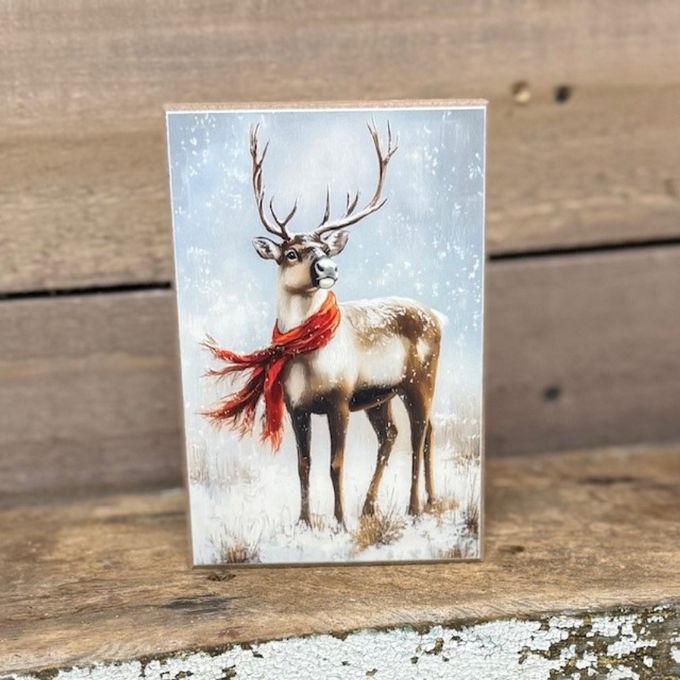 Art block with a reindeer wearing a red scarf on a wooden surface. Winter Reindeer Art Block available at Quilted Cabin Home Decor.
