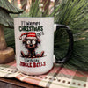 White mug with Christmas-themed design featuring a cartoon dog and humorous text, placed on a plaid surface with greenery in the background. Christmas Spirit Mug available at Quilted Cabin Home Decor.