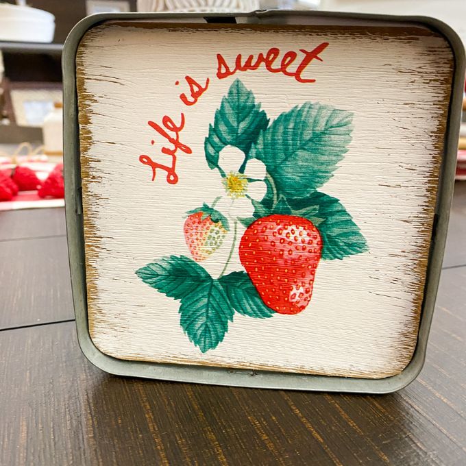 Decorative tin with strawberry design and 'Life is sweet' text on a wooden surface. Strawberry Block Sign available at Quilted Cabin Home Decor.