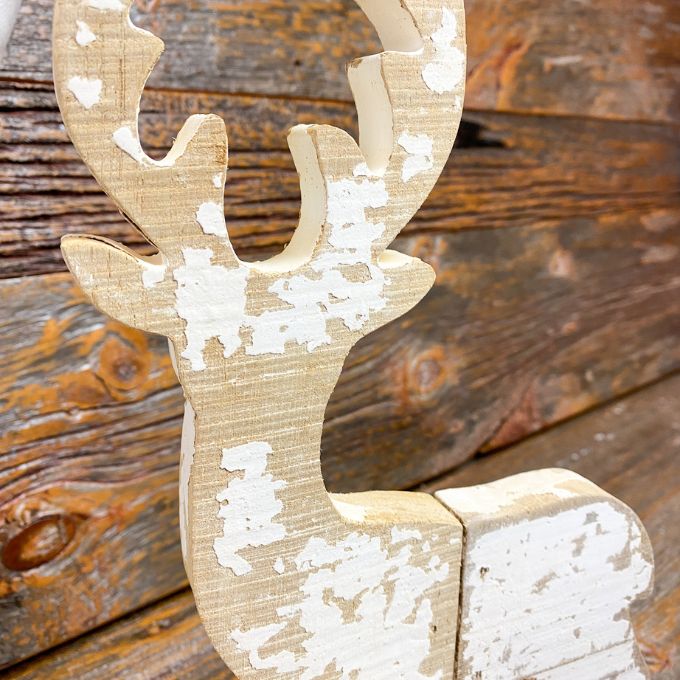 A white painted and distressed wooden reindeer that will stand as part of your christmas decor.