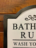 A close up of the edge of the Bathroom Rules sign