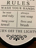 A close up of the rules on the Bathroom rules metal sign. The background of the sign is white and the words are black.