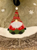 The Kringle Gnome tree skirt in green is shown. It has a festive gnome appliqued on it along with snowflakes. It is trimmed in faux fur.