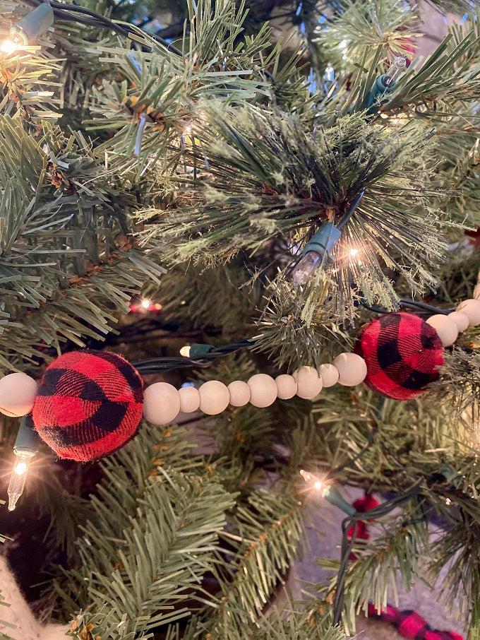 This Plain and Natural Beaded Garland is a string of natural coloured wooden beads separated by a larger black and white check or red and black check bead. Pictured is the red and black check bead.