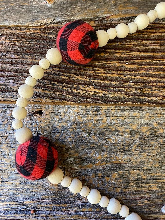 This Plain and Natural Beaded Garland is a string of natural coloured wooden beads separated by a larger black and white check or red and black check bead. Pictured is the red and black  check bead.