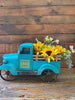  A vintage turquoise metal truck is filled with the yellow daisy pick. 