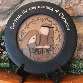 Celebrate the true meaning of Christmas wooden plate is shown. This is a wooden plate, painted in the primitive farmhouse style. This plate shows Mary and Joseph at the manger. The words Celebrate the true meaning of Christmas is painted around the rim.