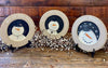 Three wooden snowman plates for your farmhouse holiday decorating. There are three styles to choose from: Snow Happy, We are Snow Blessed and When life sends a blizzard build a snowman. The edges of the plates are gray and the centre portion of the plate handpainted with the white snowman on a black background. The Snow Blessed and the Blizzard plate each have a tiny metal snowflake on them as well. 