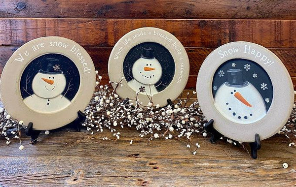 Three wooden snowman plates for your farmhouse holiday decorating. There are three styles to choose from: Snow Happy, We are Snow Blessed and When life sends a blizzard build a snowman. The edges of the plates are gray and the centre portion of the plate handpainted with the white snowman on a black background. The Snow Blessed and the Blizzard plate each have a tiny metal snowflake on them as well. 