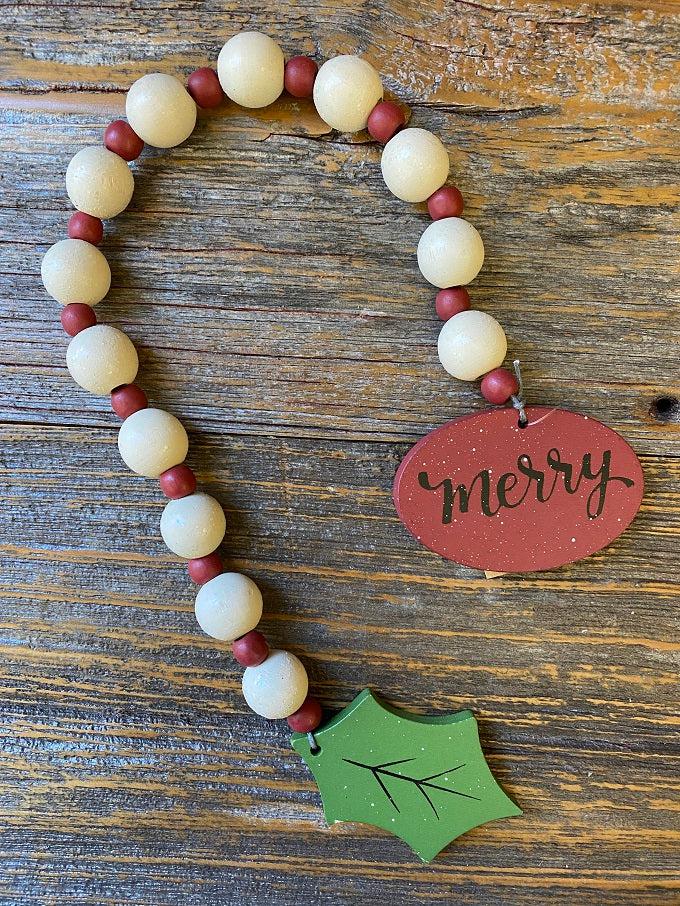 The merry wooden beaded garland is apporximately 19" long and made of white wooden beads alternately with smaller red wooden beads. At one end of the garland is a red wooden medallion with the word Merry painted on it in black lettering. At the other end is holly-like green leaf. 