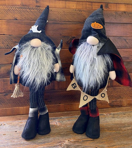 Pictured are Two 33" tall standing gnomes dressed as vampires. Both ghomes have black hats, black capes, boots and gray and black striped pants. One gnome is holding a burlap banner that says BOO. On its hat is a orange jack-o-lantern. Its cape with a stand up collar is lined with red and black plaid fabric.  The second gnome is holiding a witch's broom. On its hat is a white ghost. It's cape with a stand up collar is lined with white and black plaid fabric.