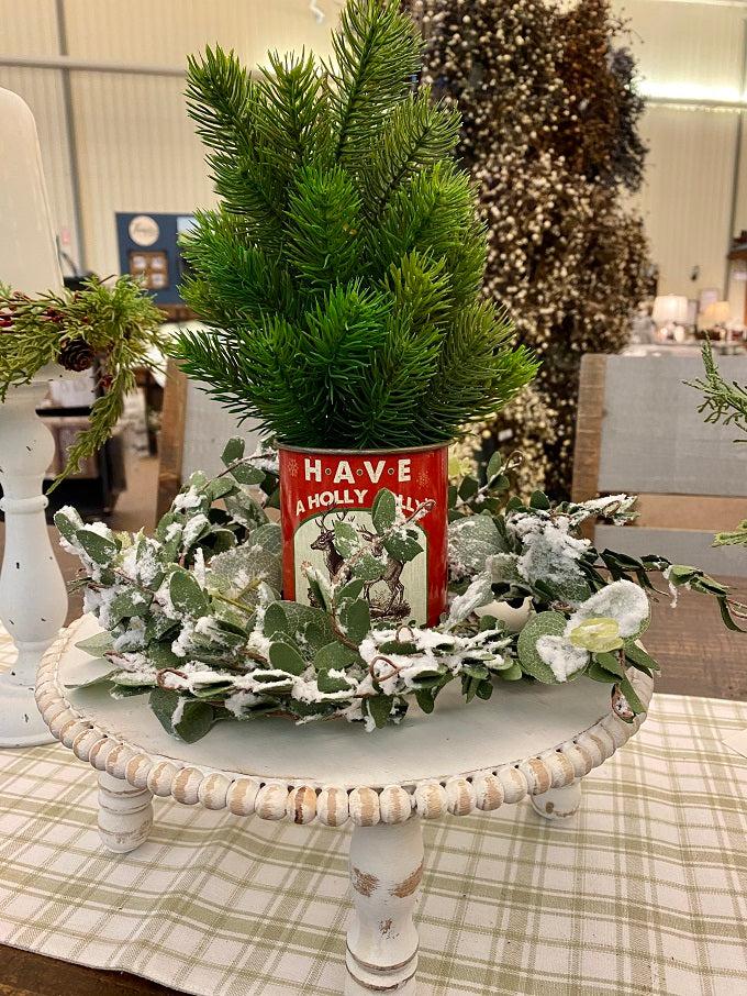  The vintage christmas metal can says Have a holly jolly christmas and has a pair of rendeer on the front. It is shown with a balsam tree and the flocked Eucalyptus wreath.