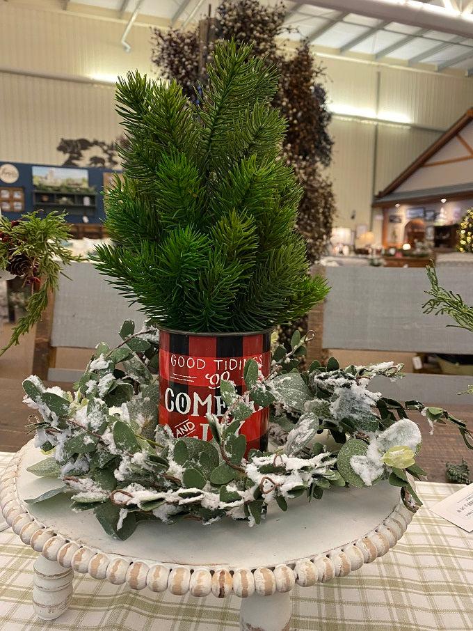 The red and black buffalo plaid vintage christmas metal can that says Good Tidings of Great Joy is shown with a balsam tree and the flocked Eucalyptus wreath.