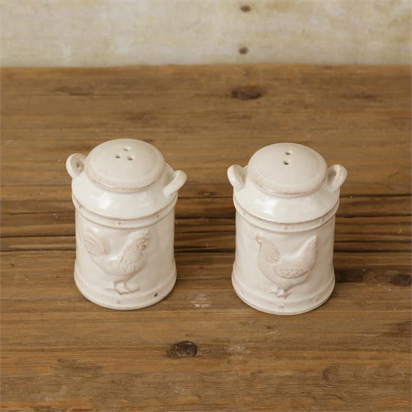 White salt and pepper shakers in the shape of milk cans. The salt shaker has an embossed rooster and the pepper shaker has an embossed chicken. The paint on them are slightly distressed.  are made of ceramic