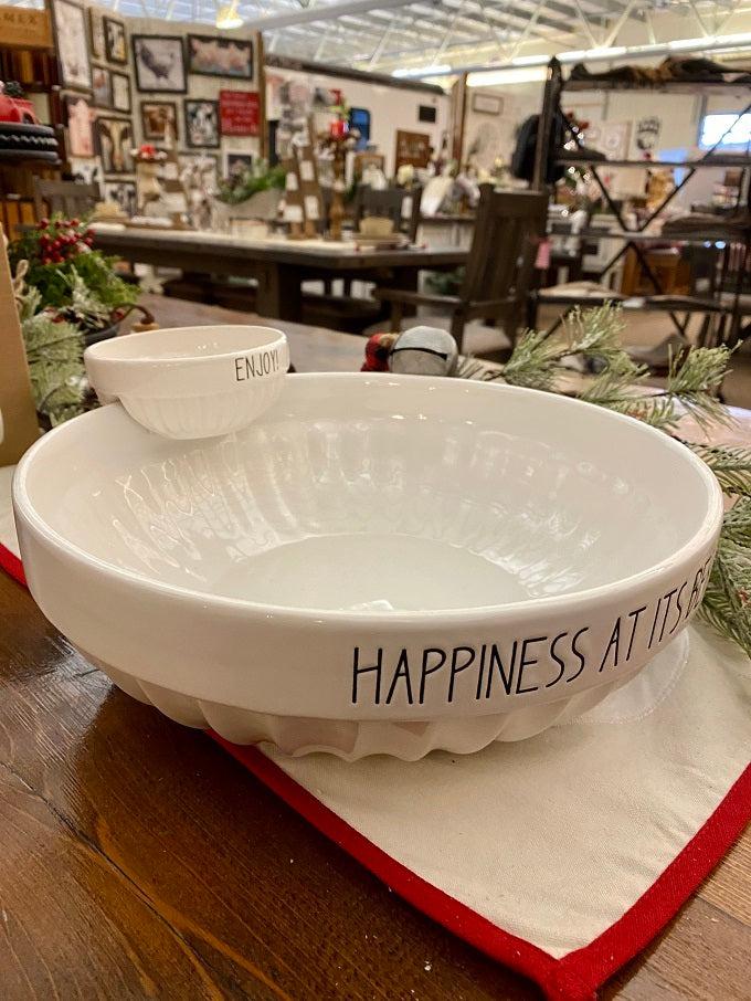 A pretty white ceramic chip and dip bowl set. The dip bowl sits on the edge of the chip bowl. The Chip bowl says Happiness at its Best and the dip bowl says Enjoy. All words are printed in black.