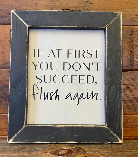A black framed sign with a wire hanger that says If at first you don't succeed, flush again.