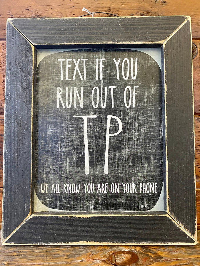 A black framed sign that says Text if you run out of TP, we all know you are on your phone.