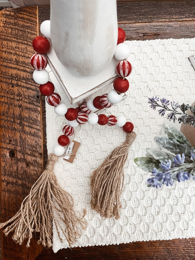 Pretty red and white striped wooden beads are mixed in with white and red one and have jute tassels on the end. Perfect to wrap around candles or add to your farmhouse decor.