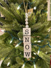  A Snow Cube Ornament with the letters of the word SNOW on each individual cube.The other three sides of the cube are painted in black and white plaid. The cubes are moveable so you can see the different sides. There is five white beads at the top of the cube stack hung on a jute rope hanger.